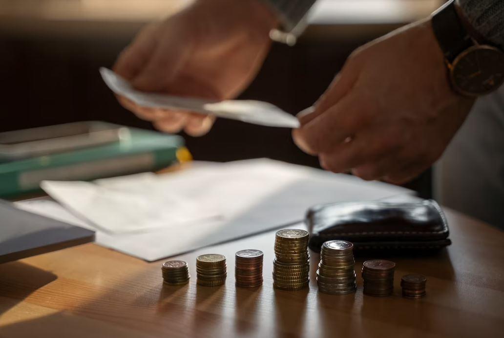 reforma da previdência: foto de home analisando documentos ao lado de pilha de moedas