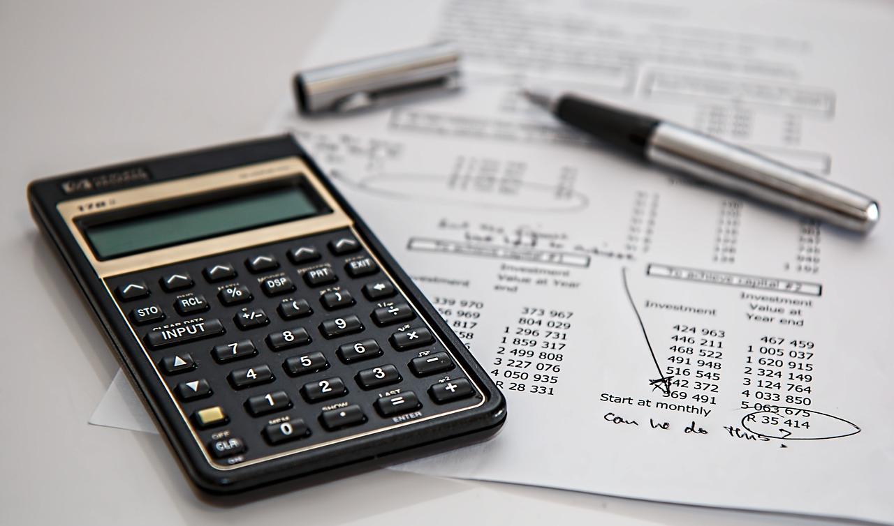 Imagem mostra uma calculadora, uma caneta e uma folha com taxas de impostos para calcular.