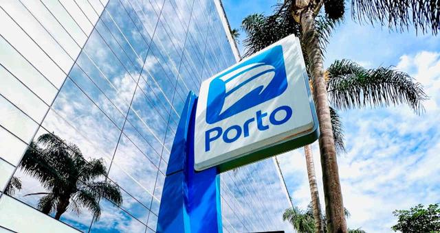 Fachada de prédio comercial com letreiro da Porto, antiga Porto Seguro, em destaque e céu azul ao fundo.