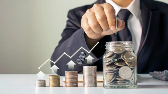 foto de homem juntando moedas em um pote: hábito de investir
