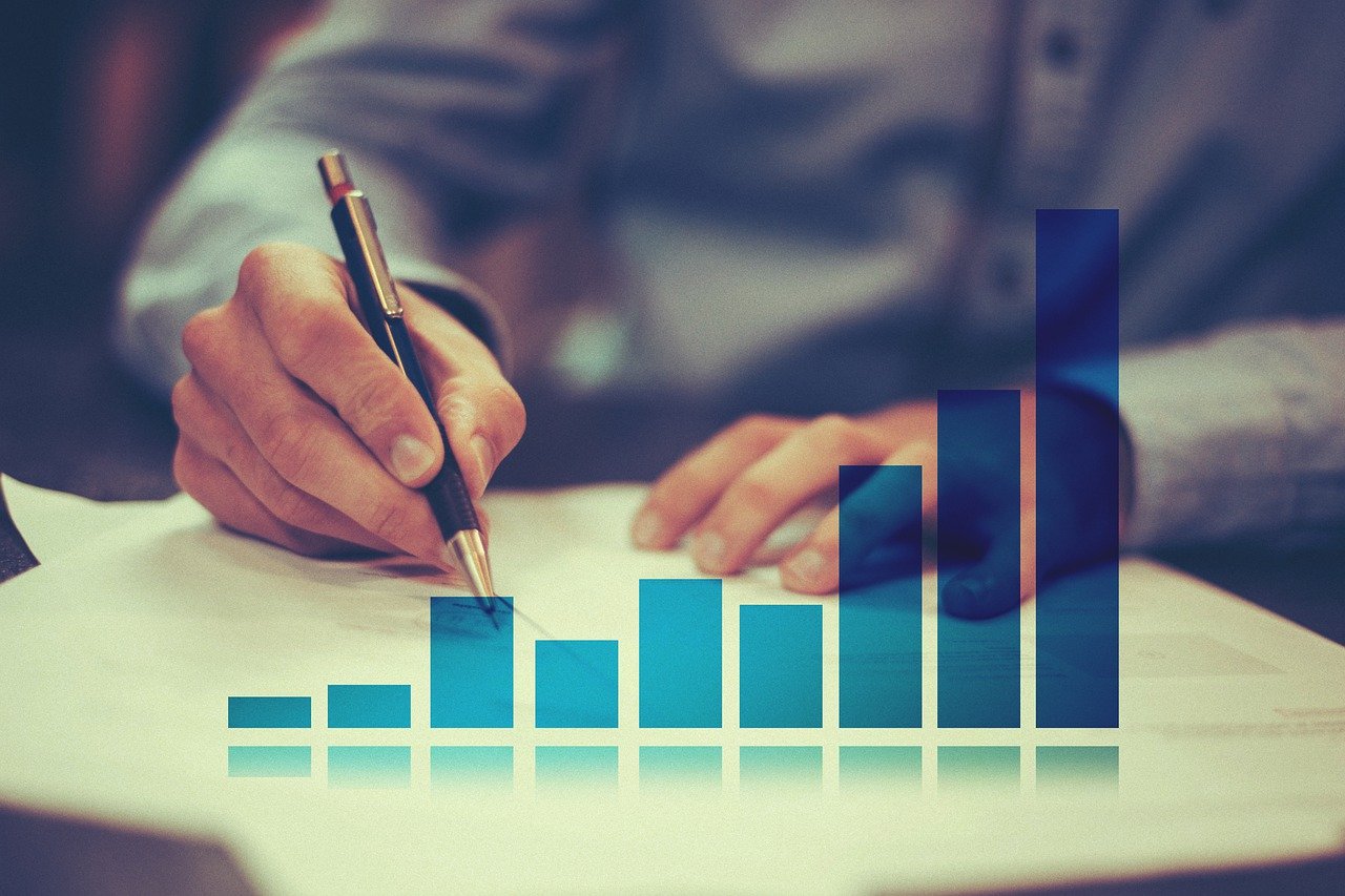 Imagem mostra um empresário analisando um contrato e gráfico. Três índices da bolsa em alta: saiba quais e como investir