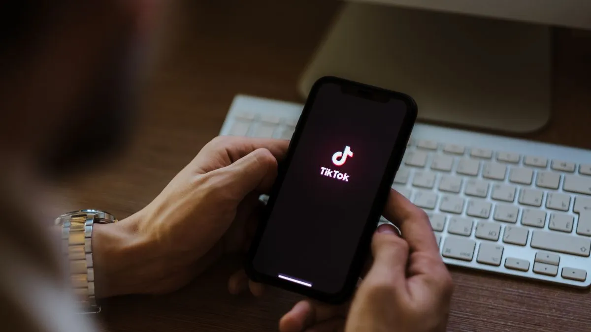 Pessoa segurando um celular com o logo do TikTok na tela.