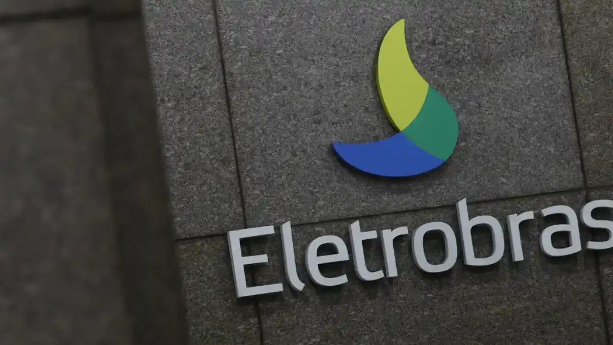 Close-up do logotipo da empresa Eletrobras na cor azul, verde e amarela, na fachada de um edifício corporativo.