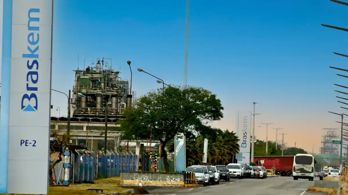 Fachada de uma unidade industrial da Braskem em um dia ensolarado, com tráfego na estrada em frente, simbolizando o balanço do 3º trimestre de 2025.