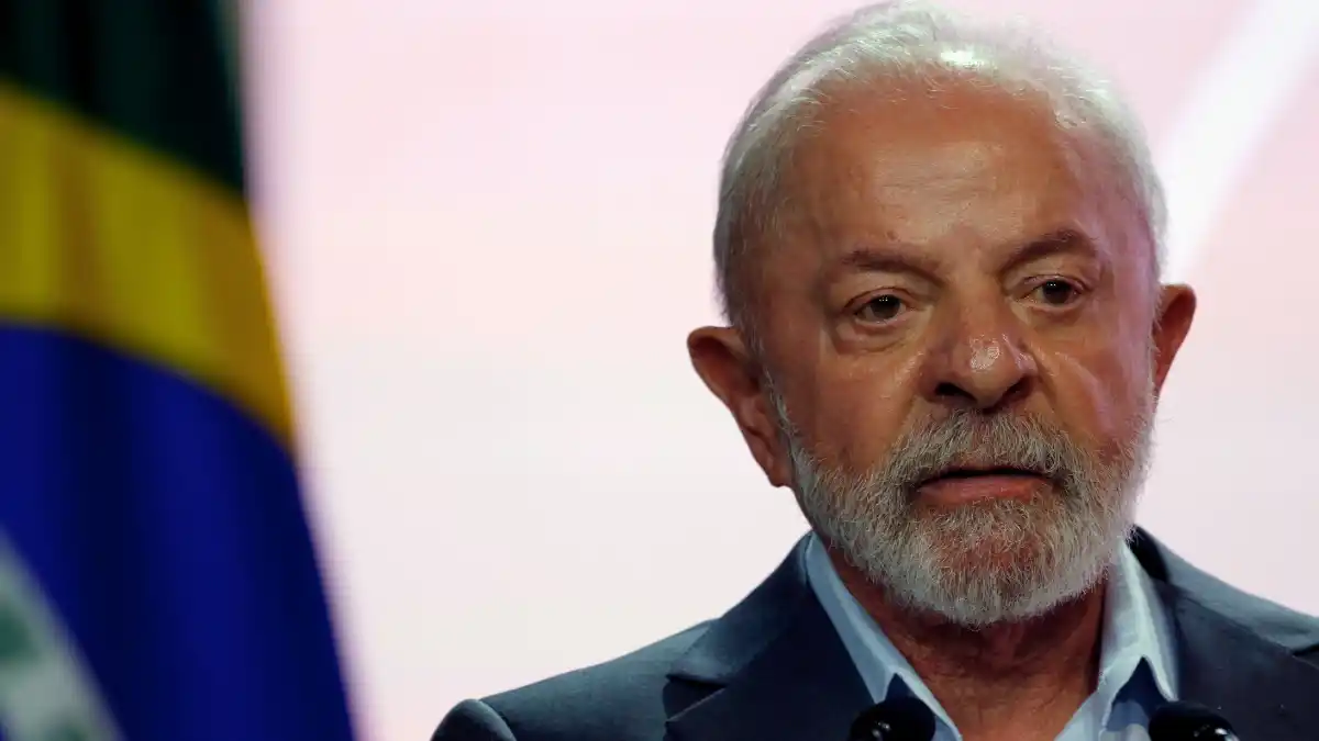 O presidente Lula (Luiz Inácio Lula da Silva) com expressão séria em um discurso, em frente a uma bandeira do Brasil, ilustrando o aumento na desaprovação do seu governo.