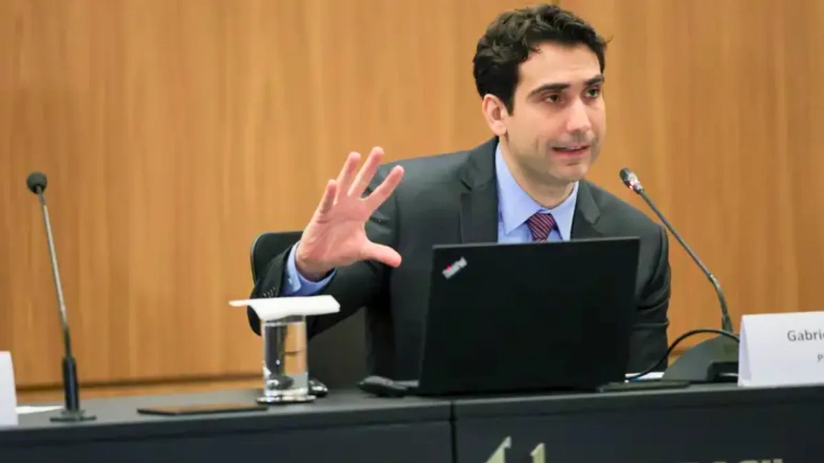 O presidente do Banco Central, Gabriel Galípolo, discursando com as mãos levantadas, defendendo o debate sobre a política monetária.