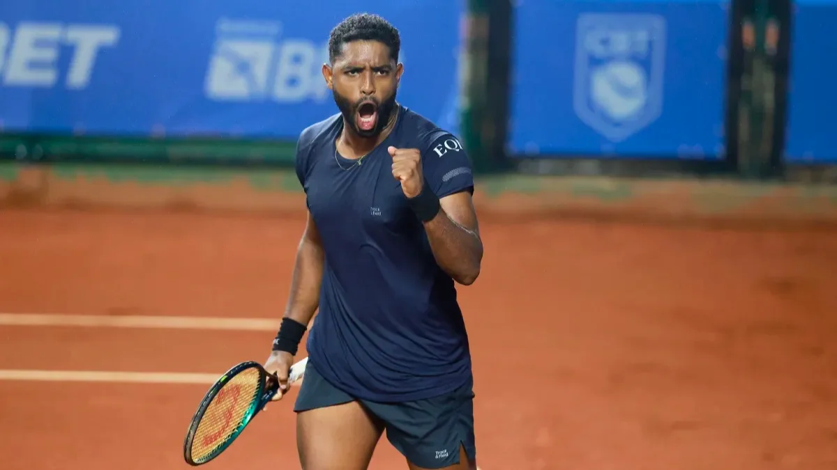 O tenista João Lucas Reis em quadra de saibro, comemorando um ponto com o punho fechado, após subir no ranking da ATP.