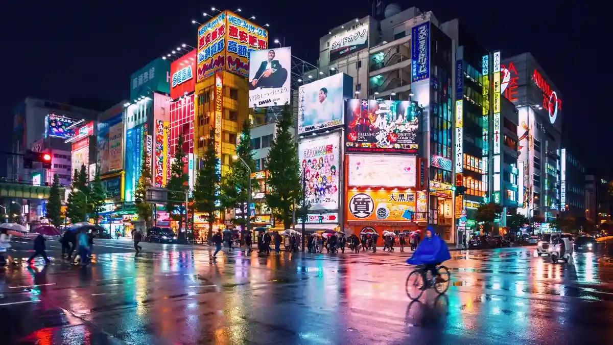 Vista noturna da rua de Akihabara em Tóquio, Japão, cheia de outdoors e luzes neon, simbolizando a virada do país que domina o noticiário global.