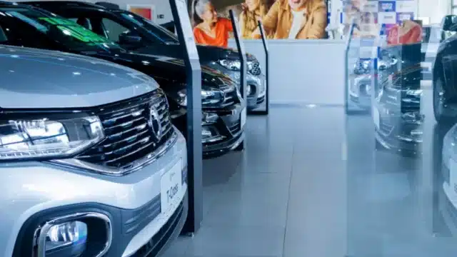 Fileira de carros novos em exposição dentro de uma concessionária moderna, ilustrando as operações de Automob M&As.