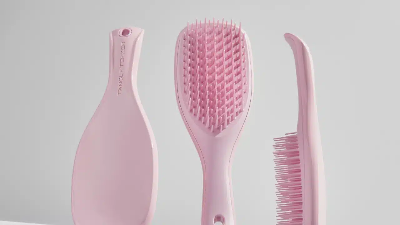 Escova de cabelo rosa da marca Tangle Teezer exibida em três ângulos diferentes, destacando o design ergonômico e as cerdas flexíveis.
