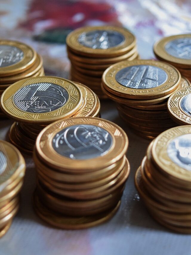 Imagem mostra um punhado de moeda sobre a mesa.