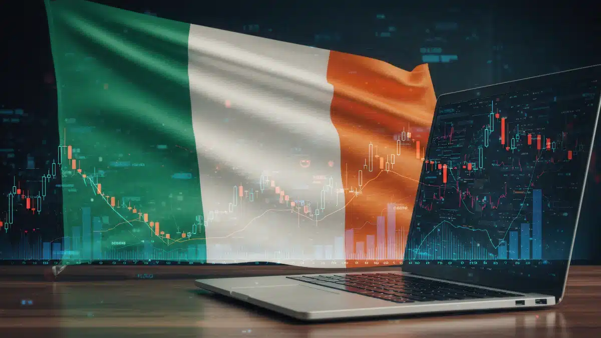 Bandeira da Irlanda sobreposta a gráficos de ações e investimentos em um laptop.