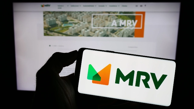 Logo da MRV em celular em frente a uma tela de computador