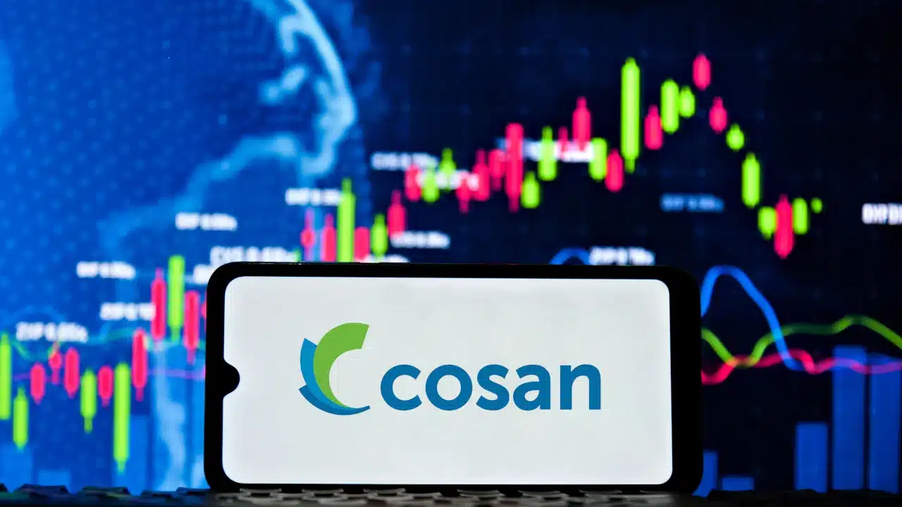 Logo da Cosan em tela de celular tendo um gráfico financeiro ao fundo
