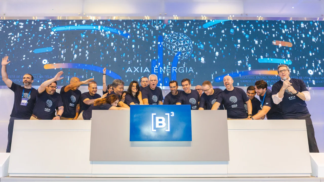 Executivos da Axia Energia comemorando no púlpito da B3 diante do painel institucional da marca, ilustrando matéria sobre o potencial de alta das ações da Axia Energia (AXIA3) segundo o Bradesco BBI.