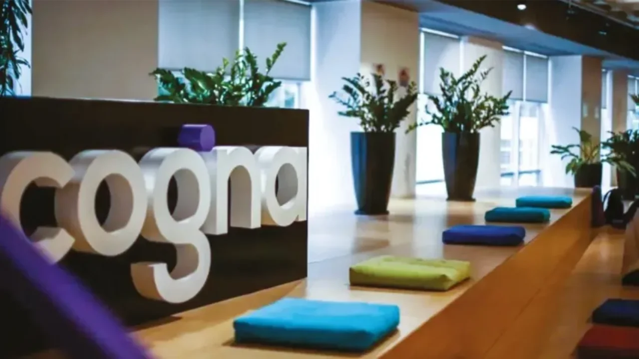Logotipo tridimensional da Cogna em destaque na recepção de escritório corporativo iluminado.