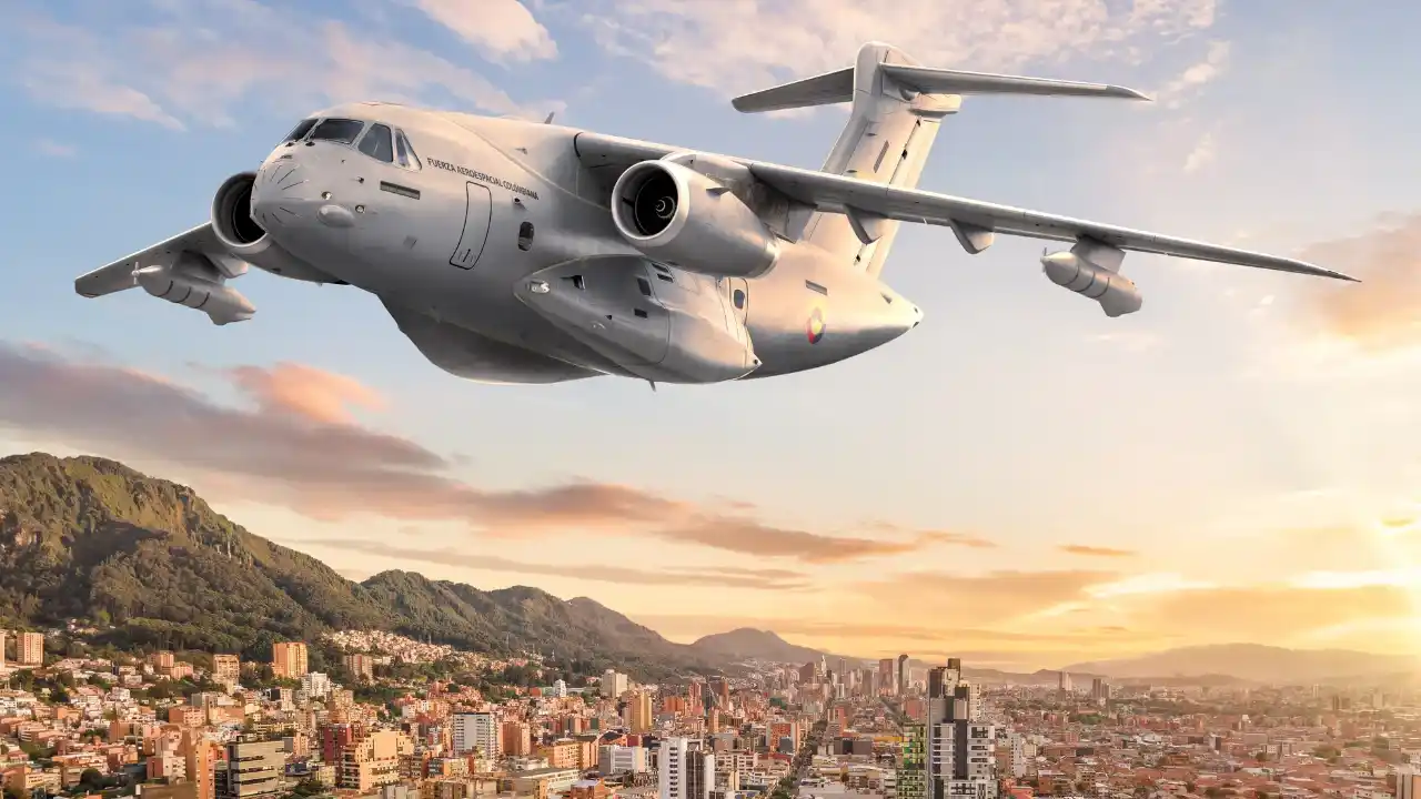 Aeronave militar Embraer C-390 Millennium em voo sobre área urbana e montanhas ao entardecer, ilustrando o balanço da Embraer no 2T26.