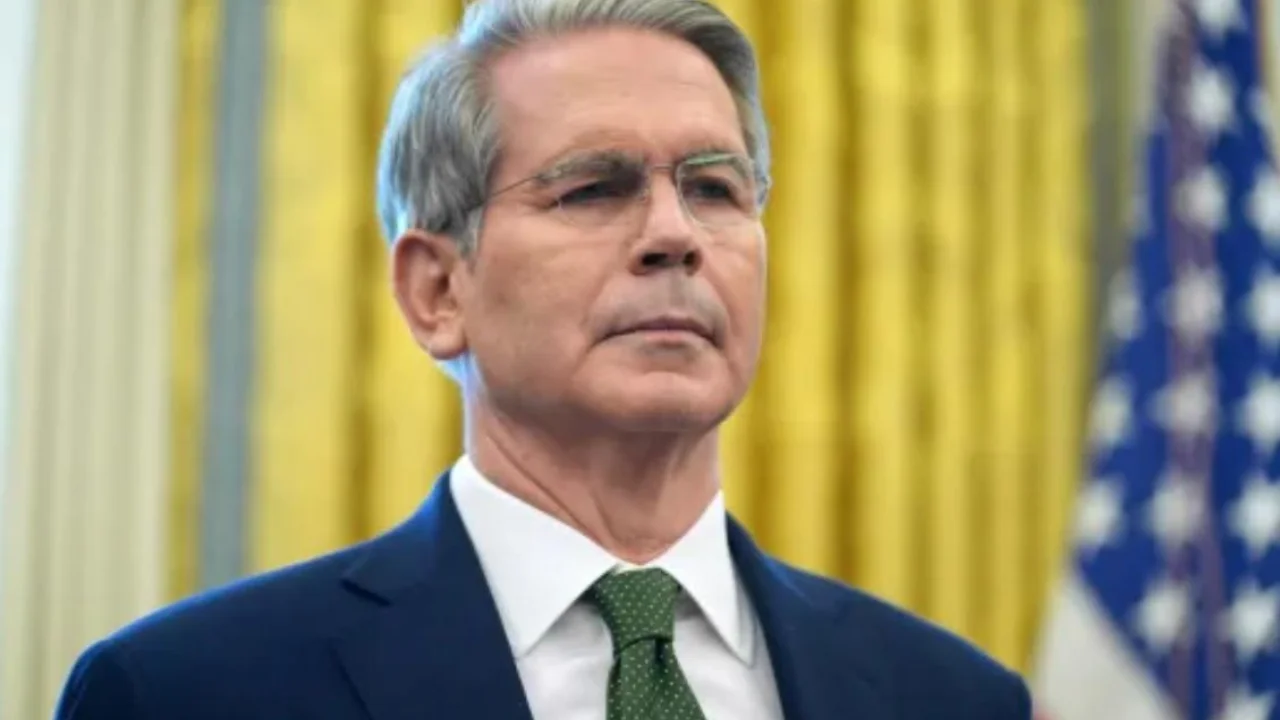 Scott Bessent, secretário do Tesouro dos EUA, em enquadramento do peito para cima com a bandeira americana ao fundo.