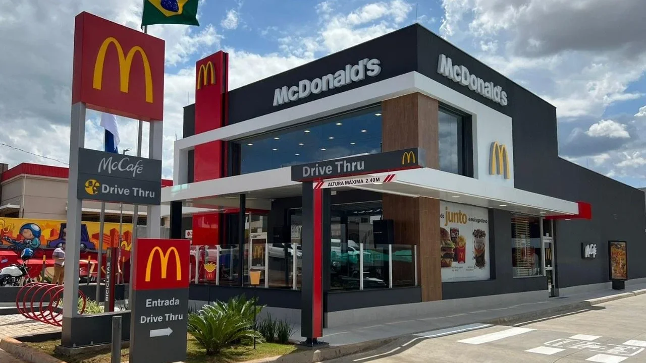 Fachada de restaurante do McDonald's (Arcos Dorados) com totem de Drive Thru e McCafé em pauta sobre relatório do BTG Pactual.