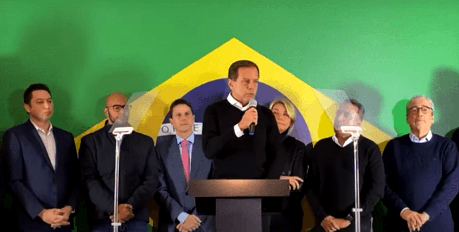 Eleições: João Dória desistiu da candidatura à presidência pelo PSDB. No foto, ele aparece falando em um púlpito com outras pessoas ao lado e a bandeira do Brasil ao fundo