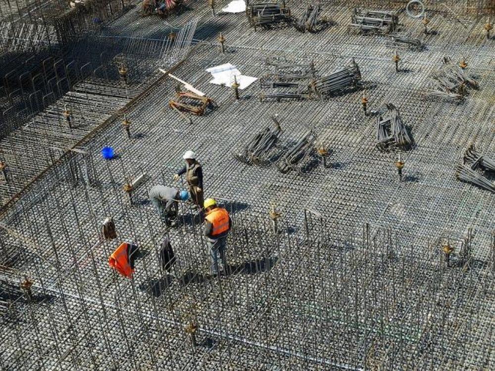Imagem mostra trabalhadores da construção em uma obra.