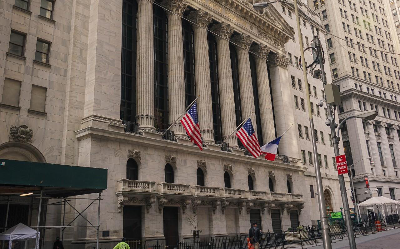 Fachada da Bolsa de Nova York (NYSE). Prédio com clunas gregas e bandeiras norte-americanas na fachada. Saiba como investir na NYSE.