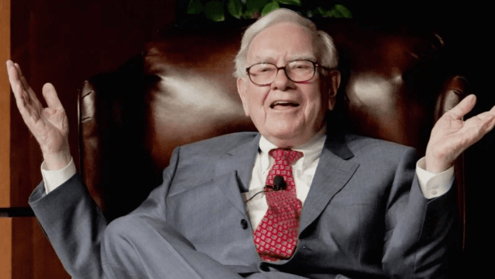 Warren Buffett sentado em sua poltrona sorrindo para a câmera