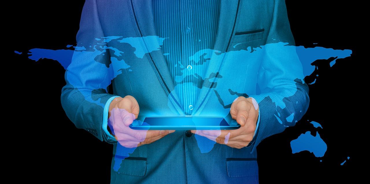homem segurando tablet com imagem projetada do mapa mundi: como investir em Fundos internacionais de investimento