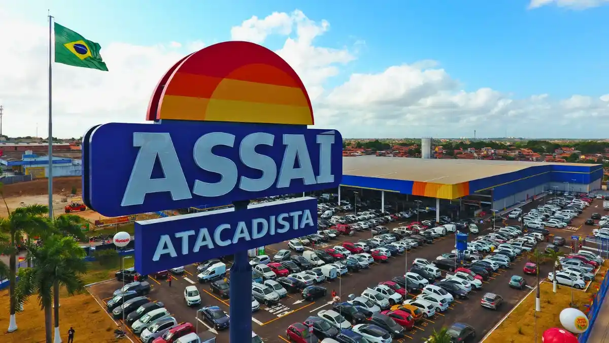 Vista externa de uma loja do Assaí Atacadista com a bandeira do Brasil hasteada, simbolizando a queda das ações (ASA3) após a compra de 10% da varejista pelos Irmãos Muffato