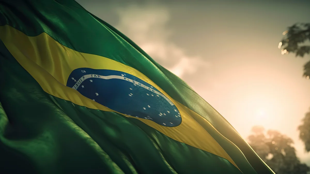 Bandeira do Brasil esvoaçando ao sol, simbolizando os fatores macroeconômicos internos, como o risco fiscal e a baixa produtividade, que mantêm a taxa de juros alta no Brasil.