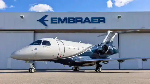 Jato executivo da Embraer estacionado em frente a um hangar com o logotipo da empresa, representando o otimismo com os resultados do 4º trimestre de 2025 (4TRI25).