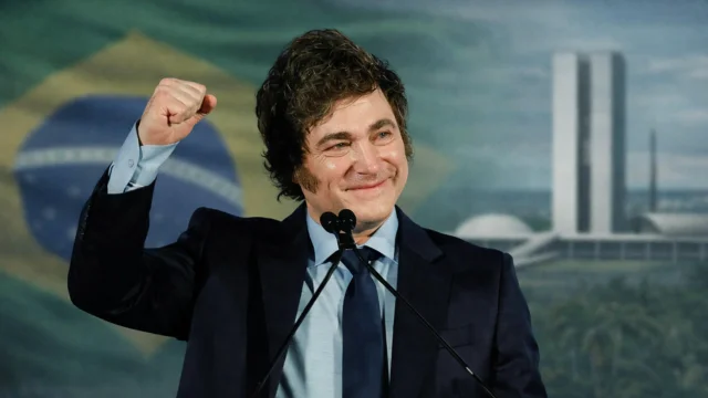 Montagem digital mostrando Javier Milei com o punho erguido à frente da bandeira do Brasil e do Congresso Nacional, ilustrando debates sobre Milei próximo governo Brasil.