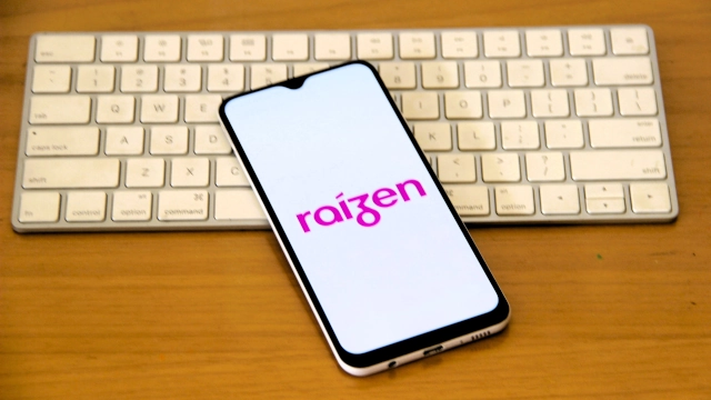 Logo da Raízen em celular junto a teclado de computador