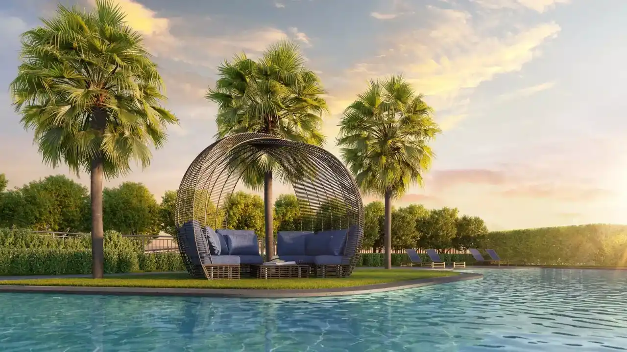 Área de lazer externa de empreendimento residencial de alto padrão da Lavvi, exibindo piscina de águas cristalinas com gazebo circular em fibra e estofados azuis ao centro, cercado por palmeiras tropicais e espreguiçadeiras ao pôr do sol.