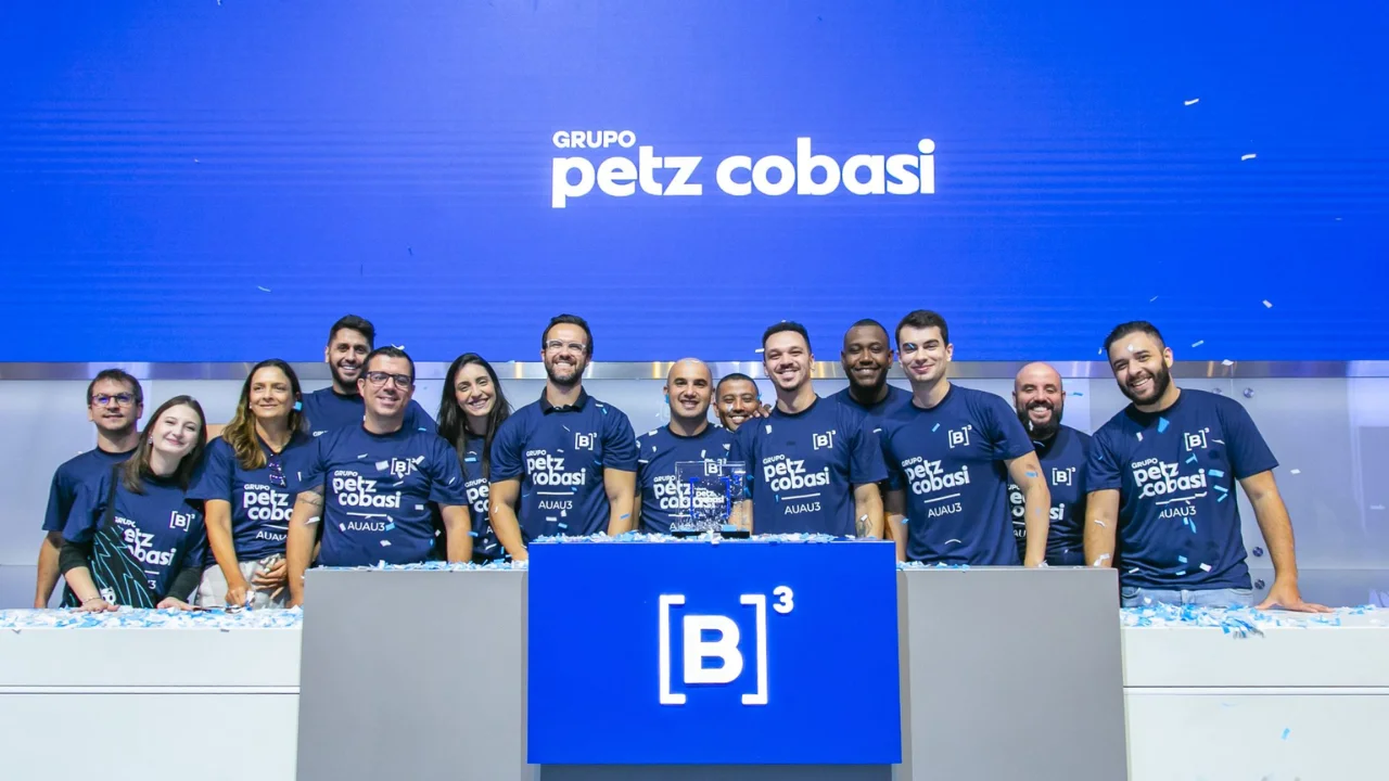 Executivos do Grupo Petz Cobasi comemorando no púlpito da B3 com camisetas estampadas com o ticker AUAU3, ilustrando matéria sobre o balanço do Petz Cobasi 2T26.